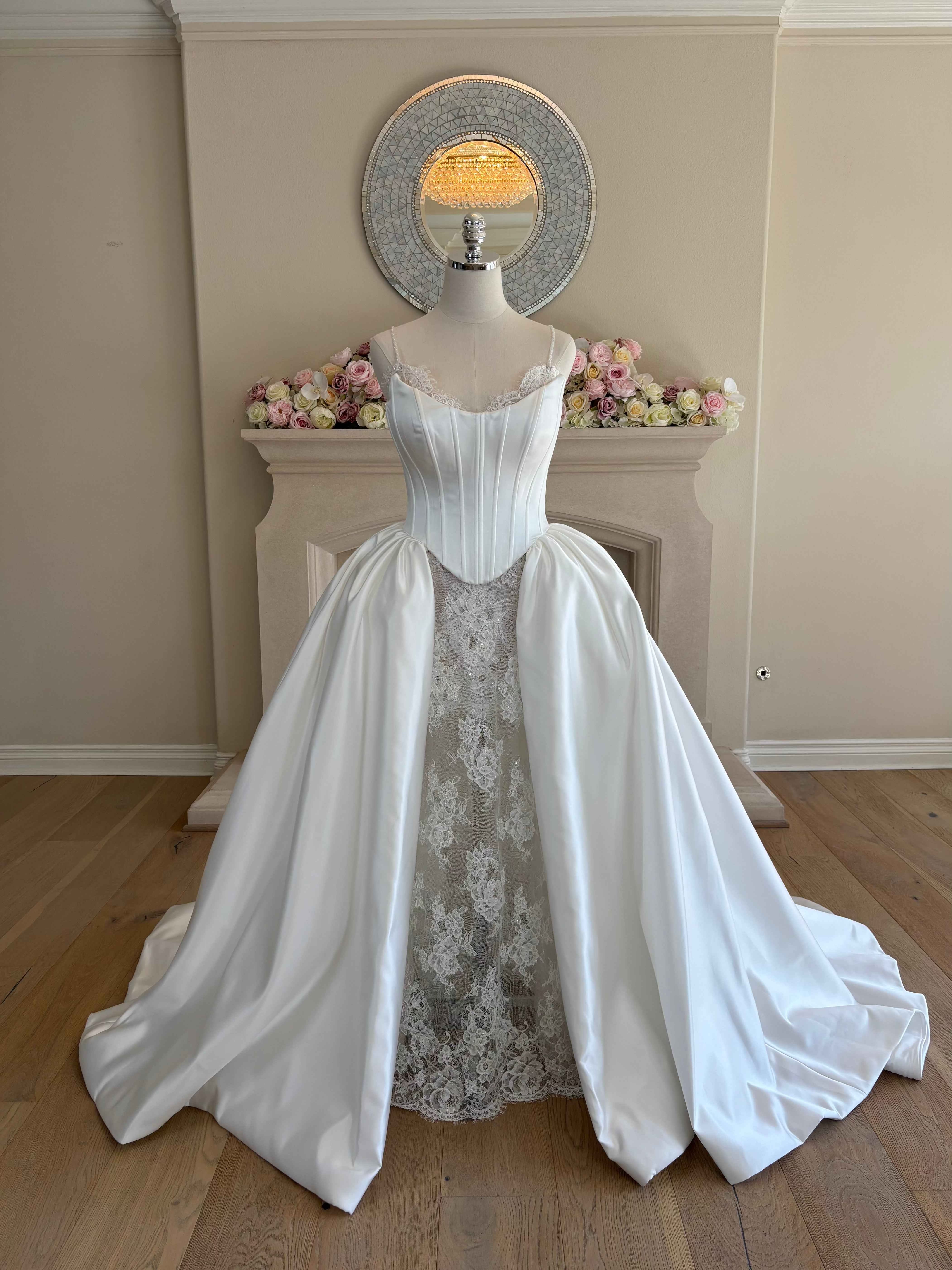 Front view of Amélie two-piece wedding gown worn with structured Mikado corset overskirt in an A-line silhouette over a french lace dress.