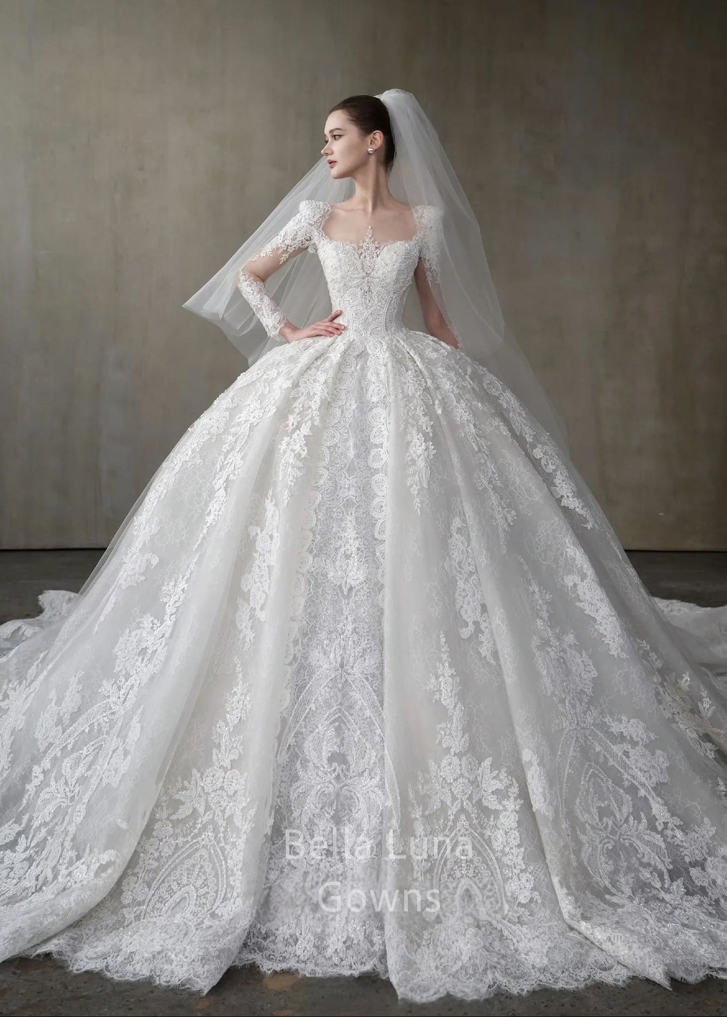 Front view of Genevieve off-white lace bridal ball gown with square neckline, long sleeves, full skirt, and veil styling