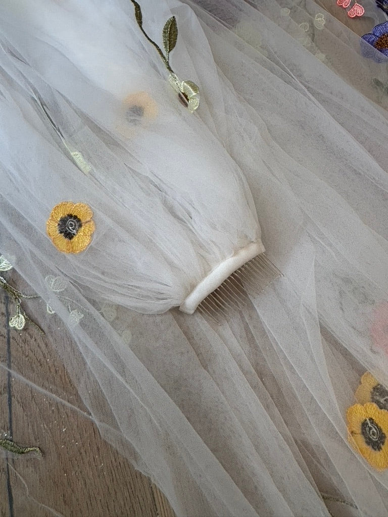 Close-up of the ivory-wrapped metal comb and embroidered flowers on the Meadow Reverie veil