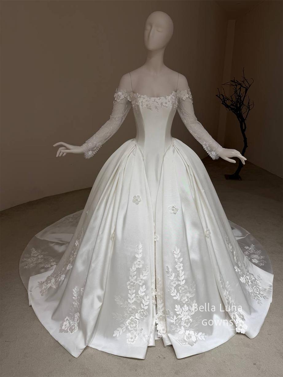Front view of the Aveline off-white satin basque-waist ball gown with long lace sleeves and floral-and-leaf appliqués