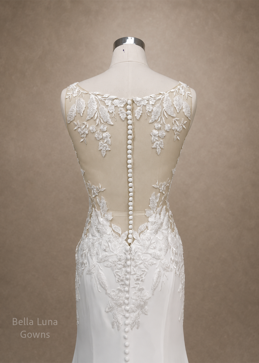 valessine-illusion-button-back-floral-applique-detail.webp
Alt: Close-up of Valessine sheer illusion back with embroidered floral appliqué and fabric-covered buttons