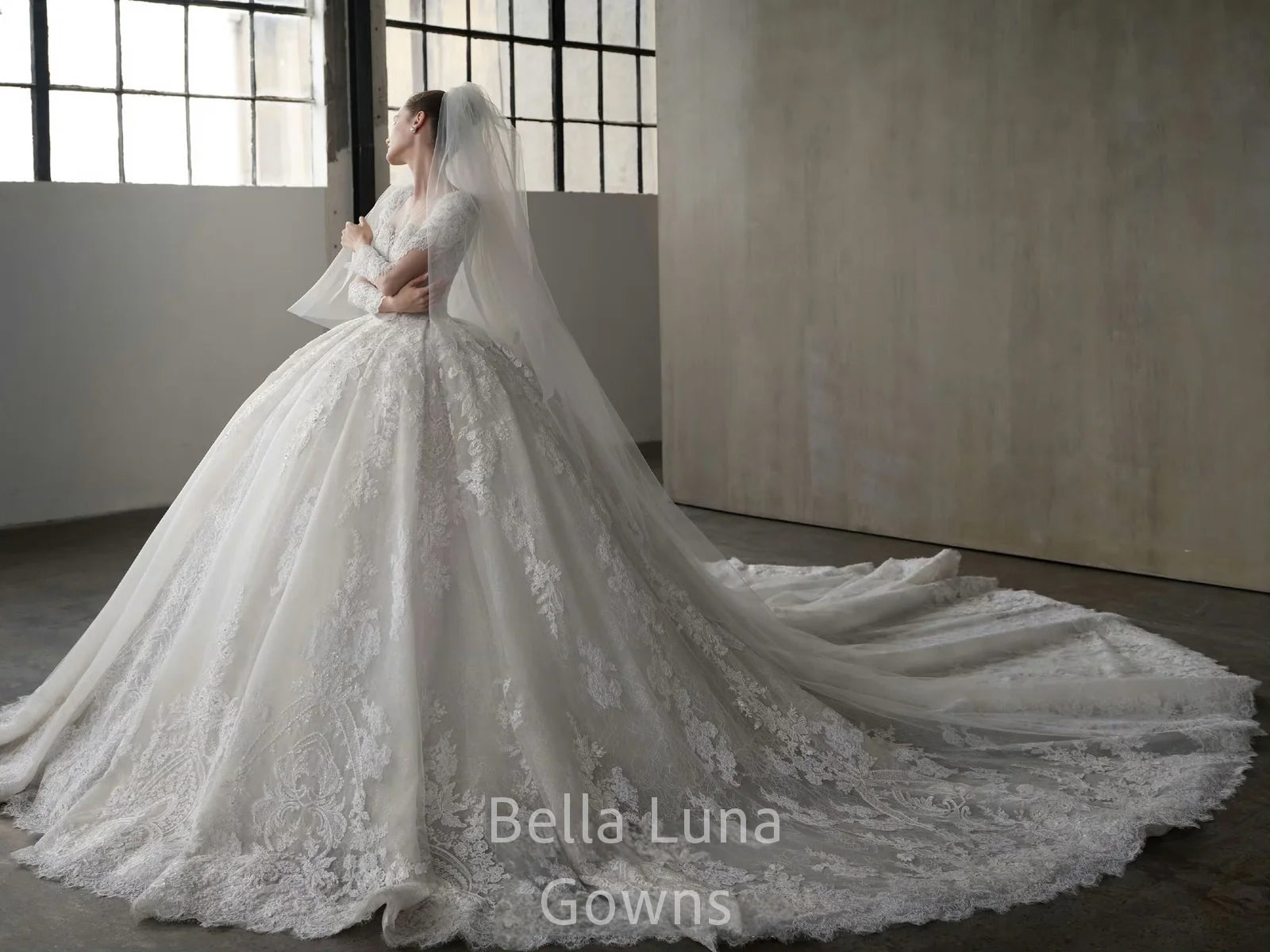 Side view of Genevieve off-white lace ball gown with square neckline, long sleeves, full skirt, and cathedral-style train