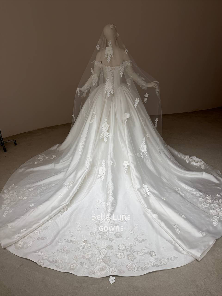 Back view of the Aveline off-white satin ball gown wedding dress with a basque waist, lace-up corset back, lace sleeves and chapel train