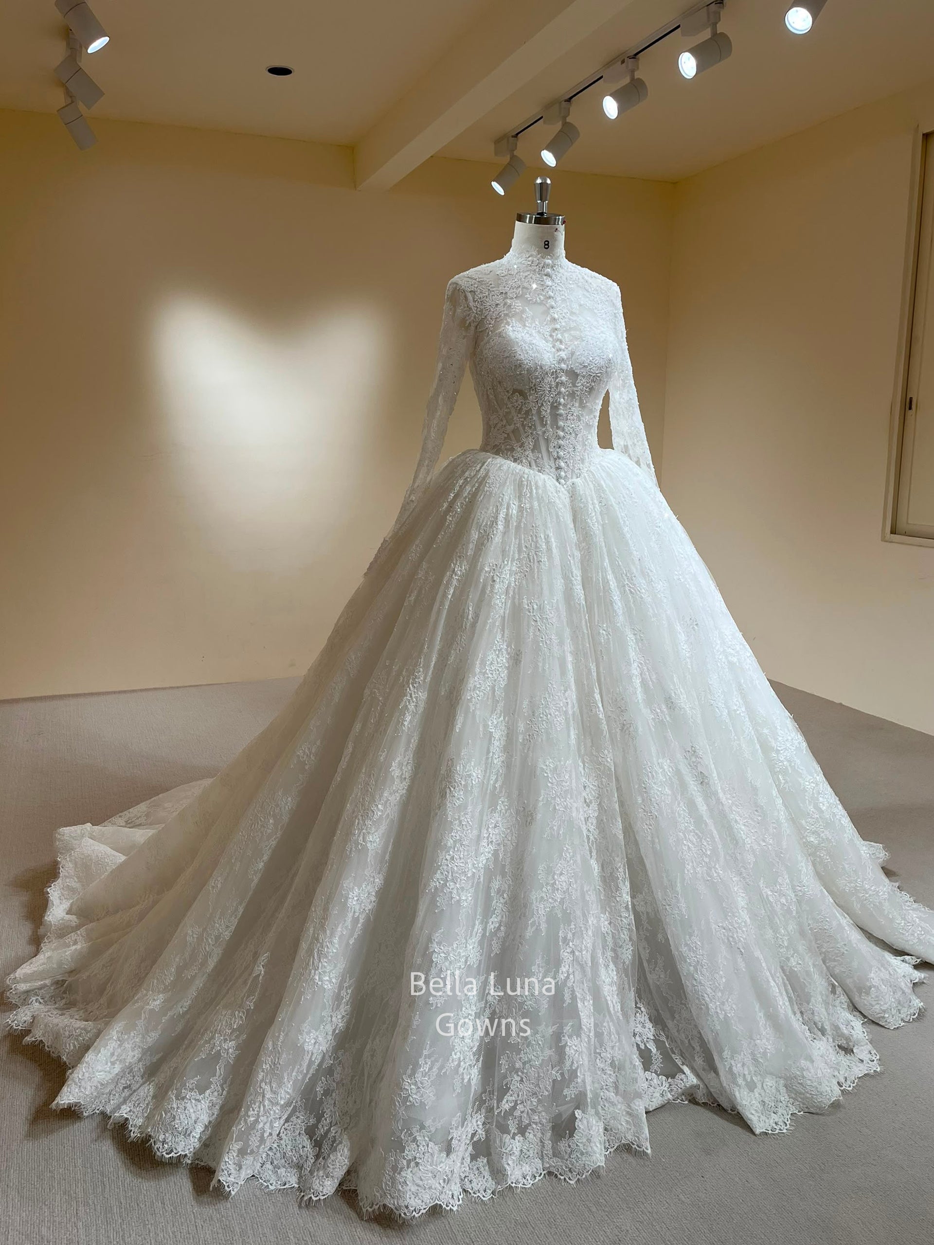 Front three-quarter view of the Theodora high-neck French lace ball gown with long sleeves and basque waist